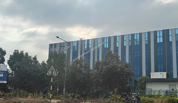 Modern multi-story commercial building with a blue and grey glass facade located near the Purva Northern Lights residential area