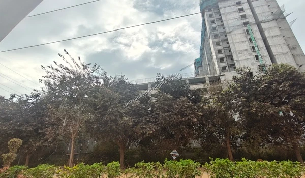 View of a high-rise building under construction with safety nets and trees in the foreground near the Purva Northern Lights location