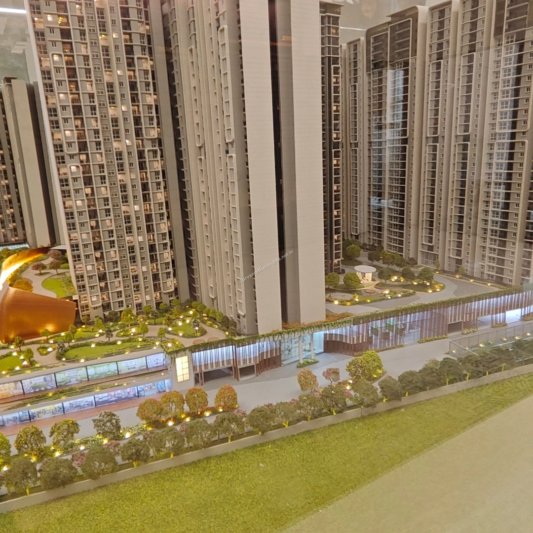 Detailed view of the illuminated ground-level commercial facade and the towering residential blocks behind it at the project miniature