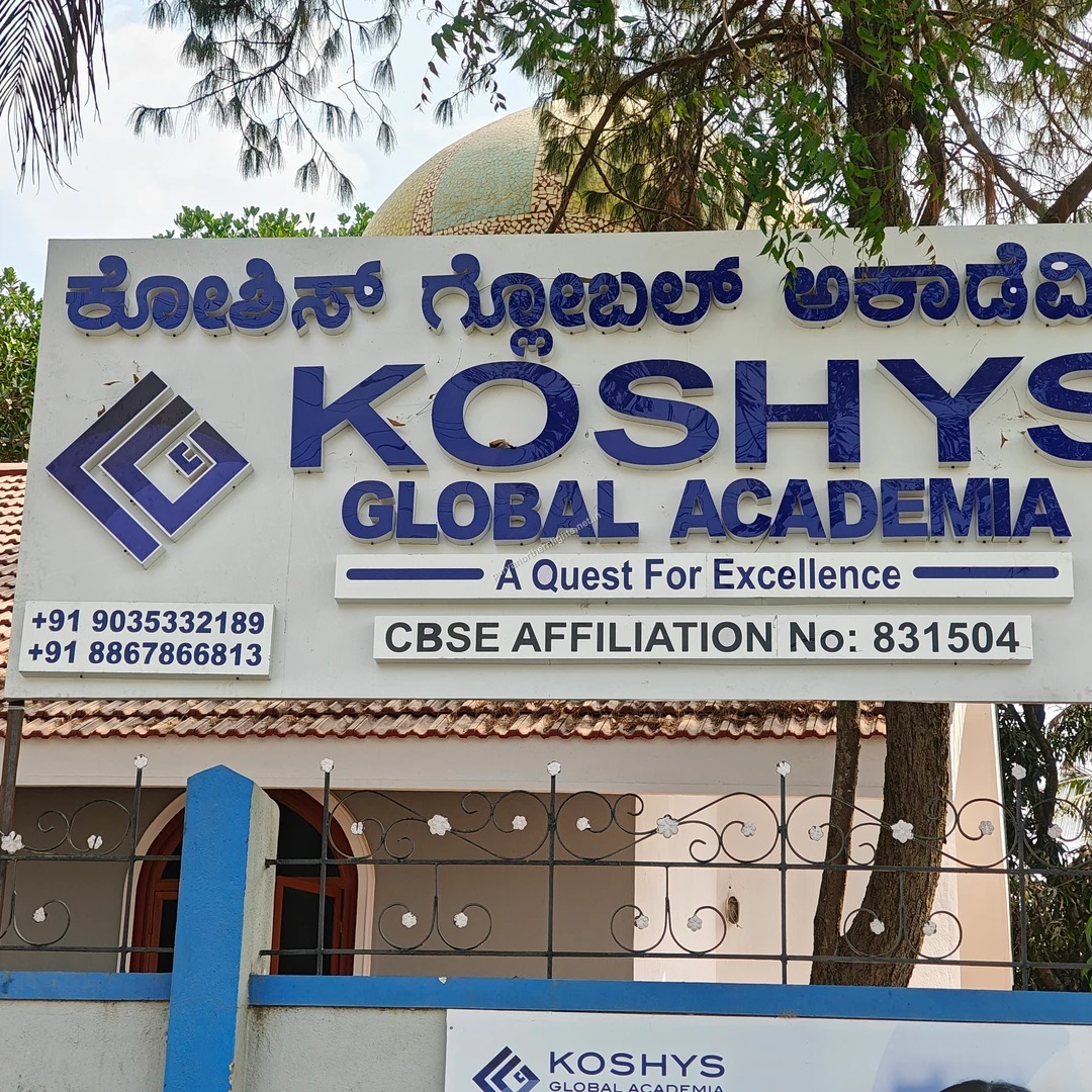 Koshys Institute Display A bright daytime view of the Koshys Global Academia signage with its blue logo and motto A Quest For Excellence.