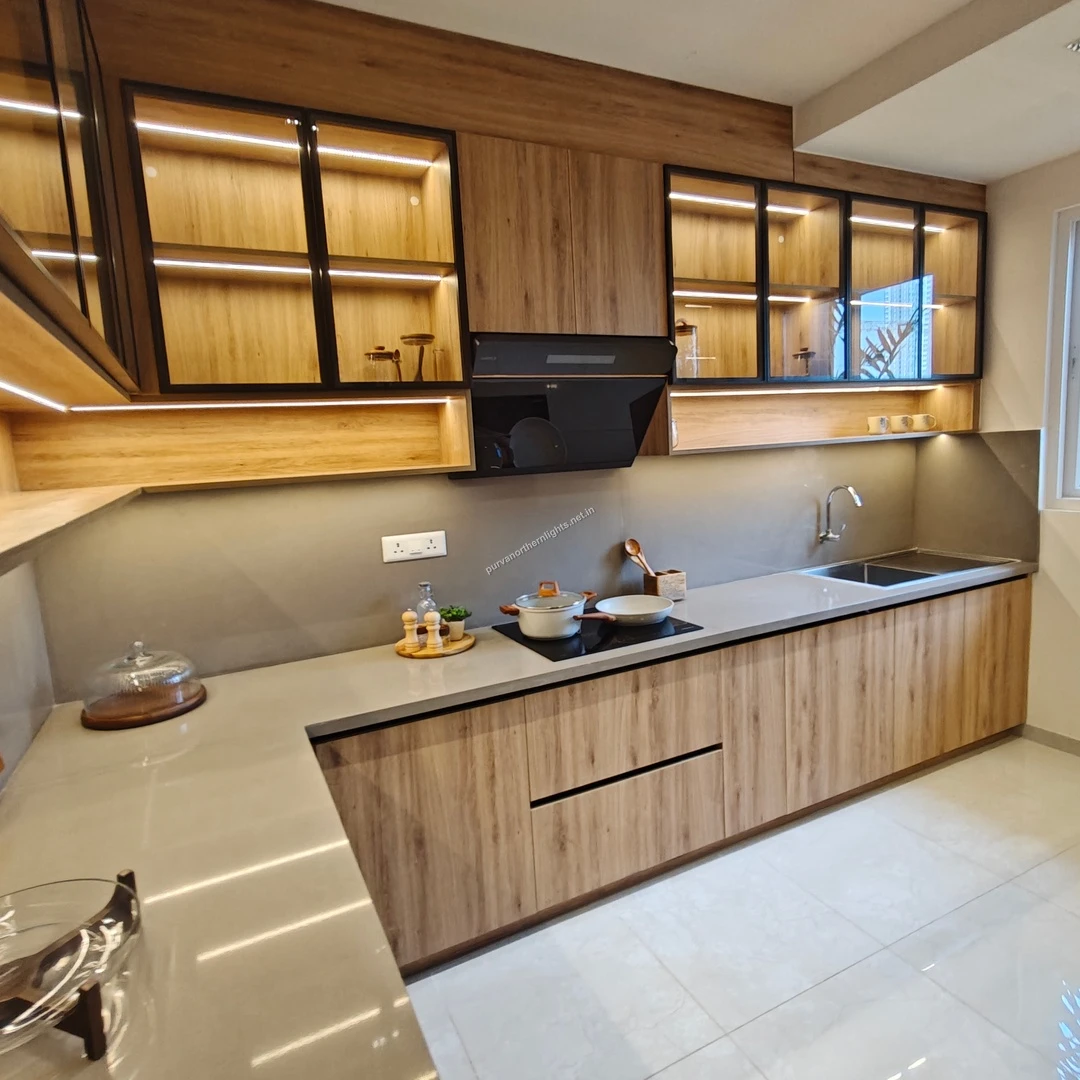 Detailed view of the modular kitchen at Purva Northern Lights featuring wooden cabinetry, glass shutters with LED lights, and a sleek grey countertop