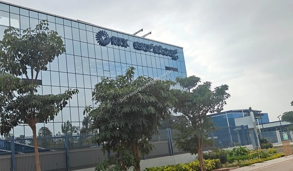 Angled view of the RTX office building showcasing its reflective blue glass architecture and dual-language signage near Purva Northern Lights