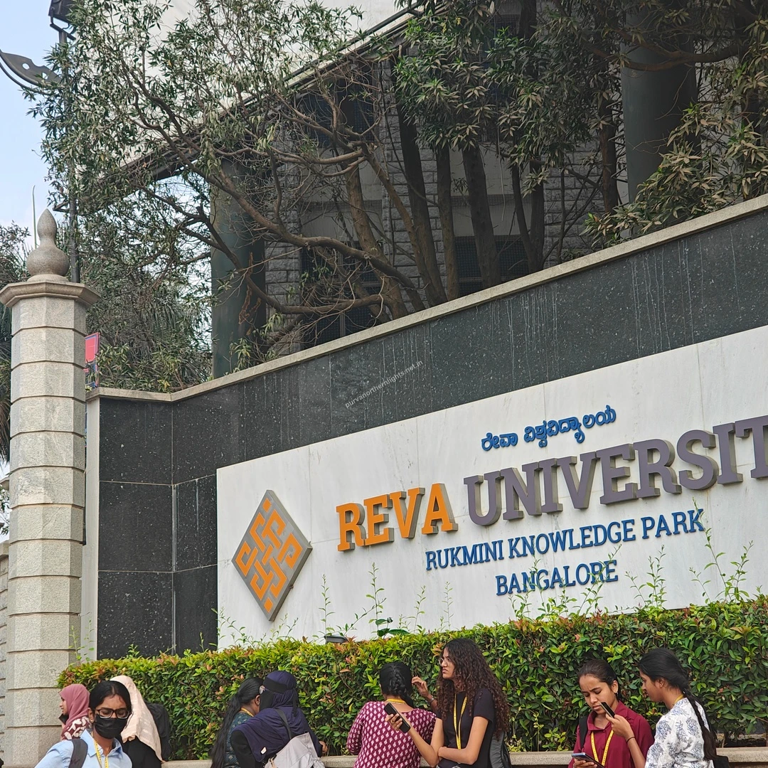 REVA Campus Facade The polished campus boundary wall displaying the REVA University name with lush green bushes planted along the base.