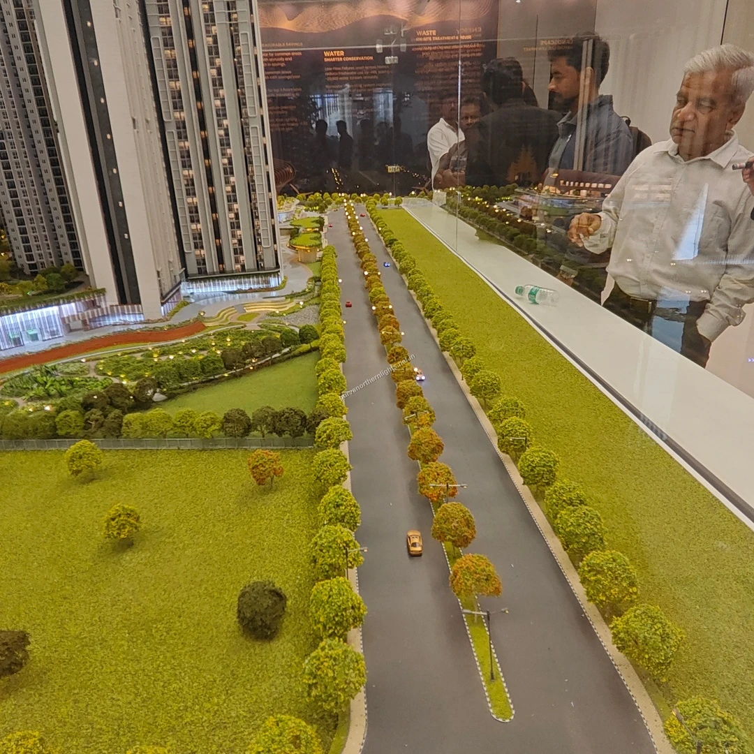Visitors observing the miniature model of the long tree-lined approach road and expansive green lawns at Purva Northern Lights captured on mar 13