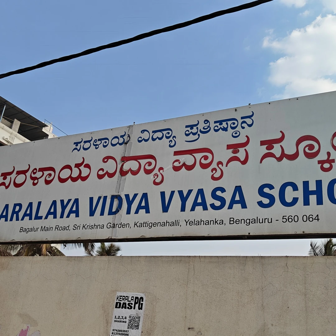 Vidya Vyasa Hoarding A wide shot of the Saralaya Vidya Vyasa School hoarding displaying its tree logo and full address on a sunny Mar 13 walk.